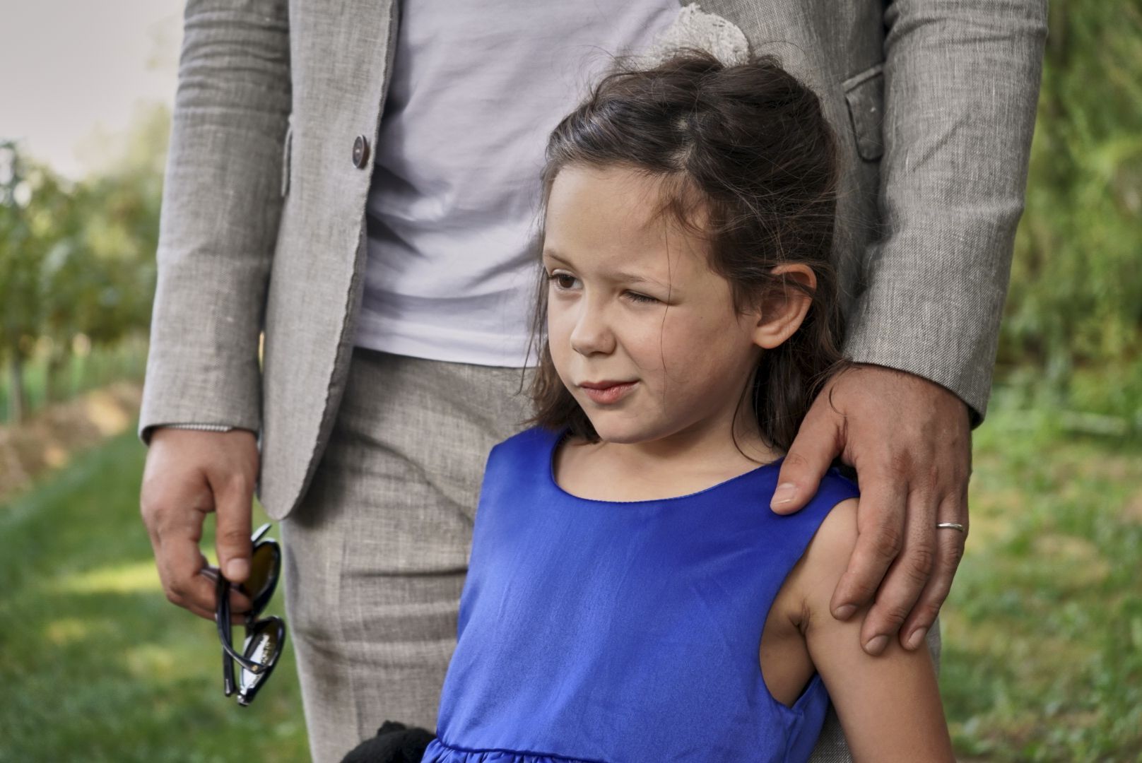 Bambina in abito blu con la mano del papà sulla spalla a un matrimonio
