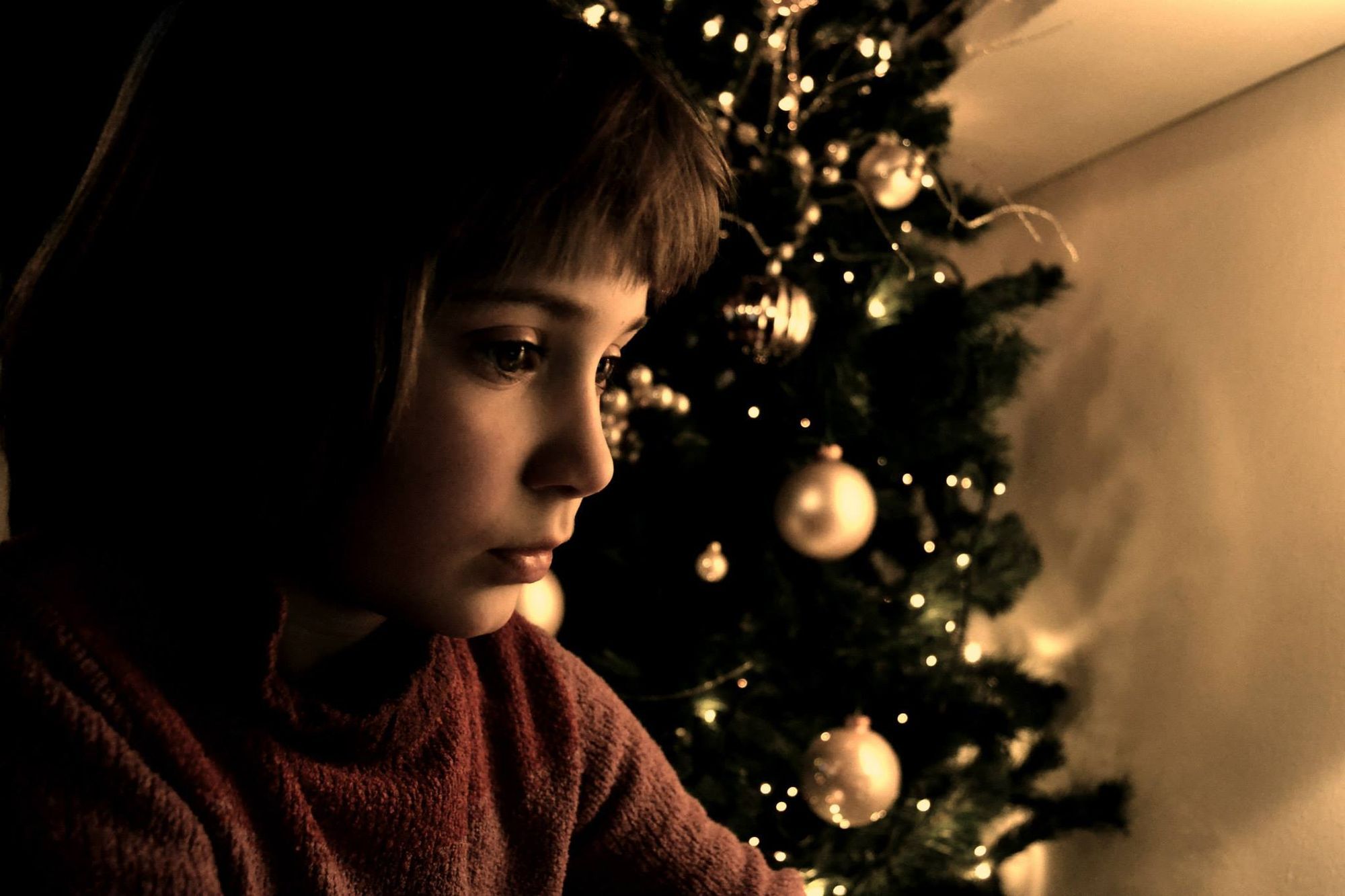 Bambina vicino all'albero di Natale, luce calda