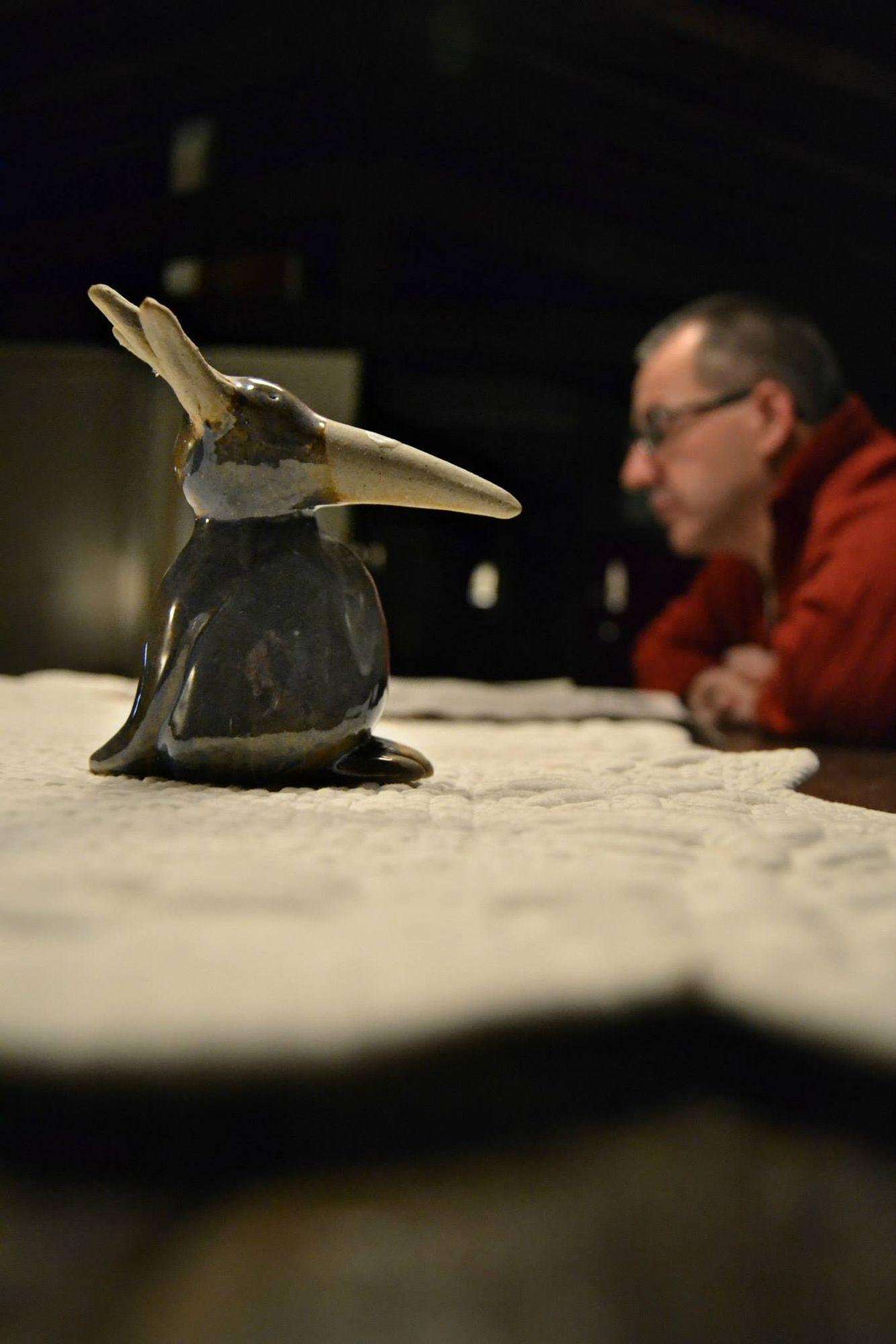 Uccellino di ceramica in primo piano e un uomo sullo sfondo