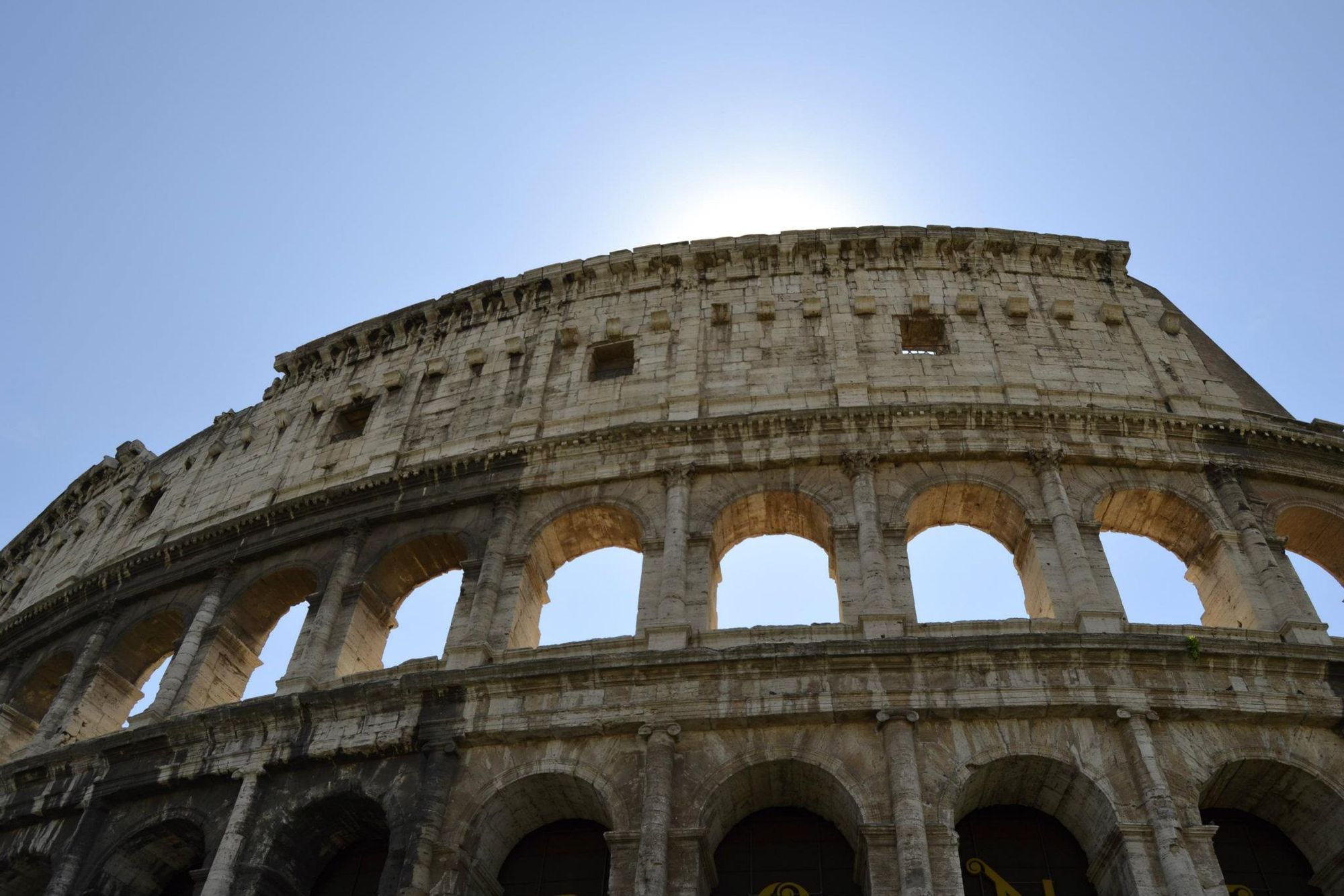Il Colosseo visto dal basso, sole dietro il muro