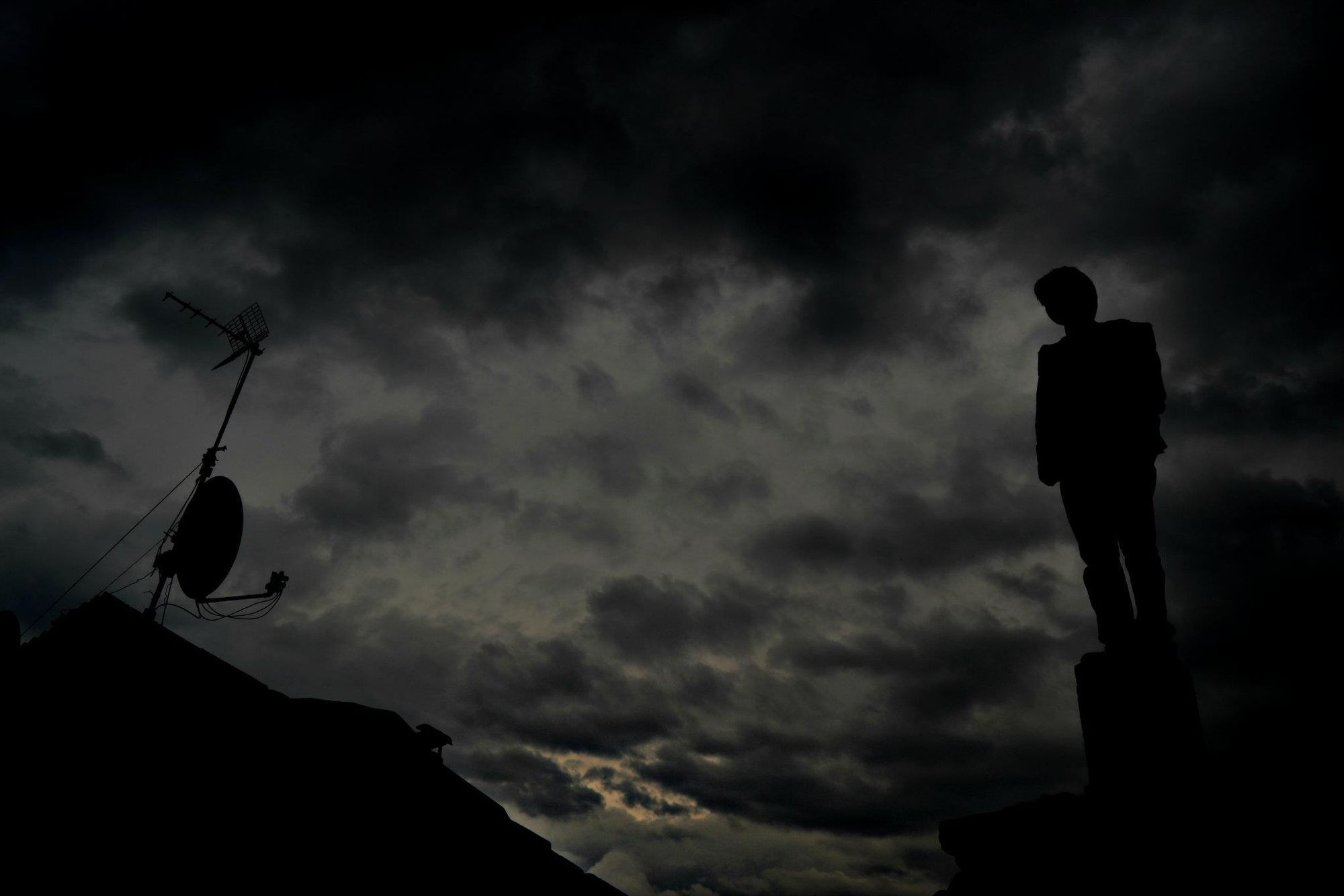 Figura in silhouette su un tetto sotto le nuvole