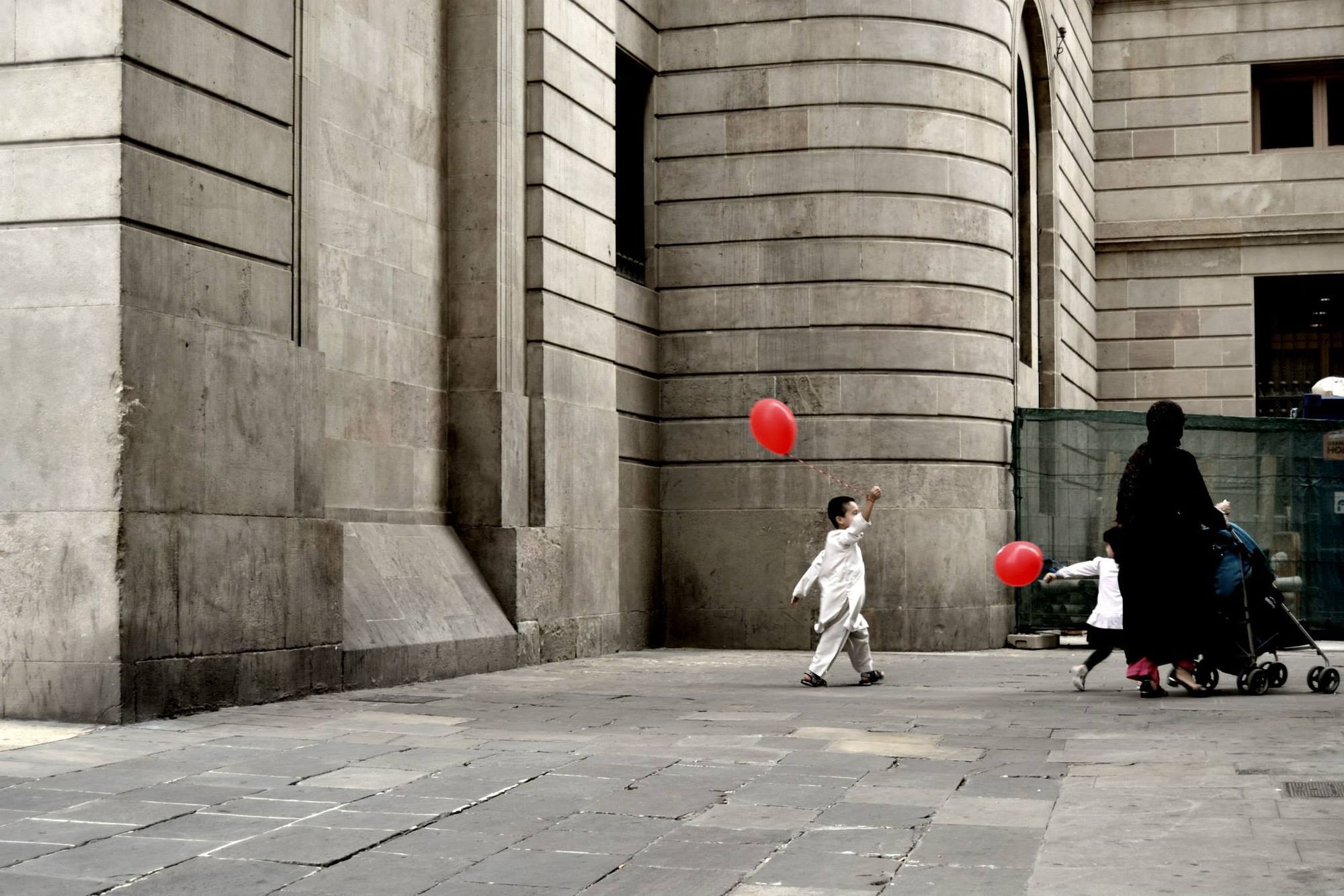 Bambino con un palloncino rosso in una piazza di pietra